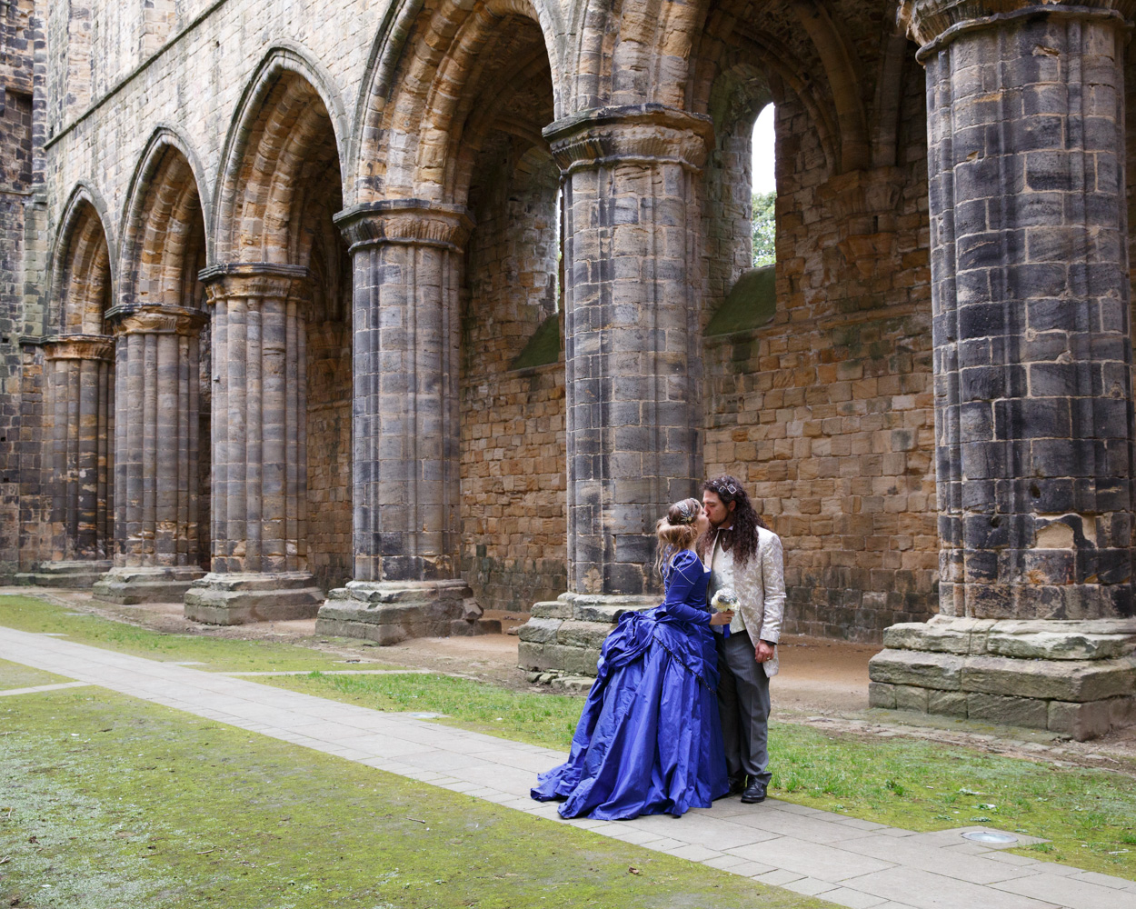 Couple portrait among the tall stone columns of Kirkstall Abbey