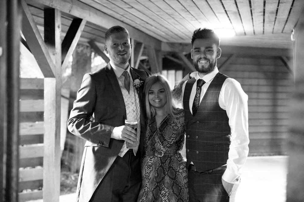 Matt and two friends pose for a relaxed black-and-white portrait at the wedding reception.