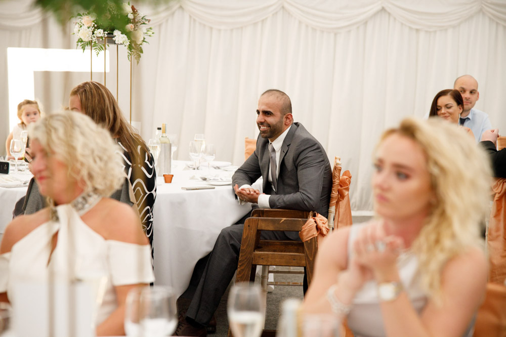 A guest smiling warmly at their table during the speeches.