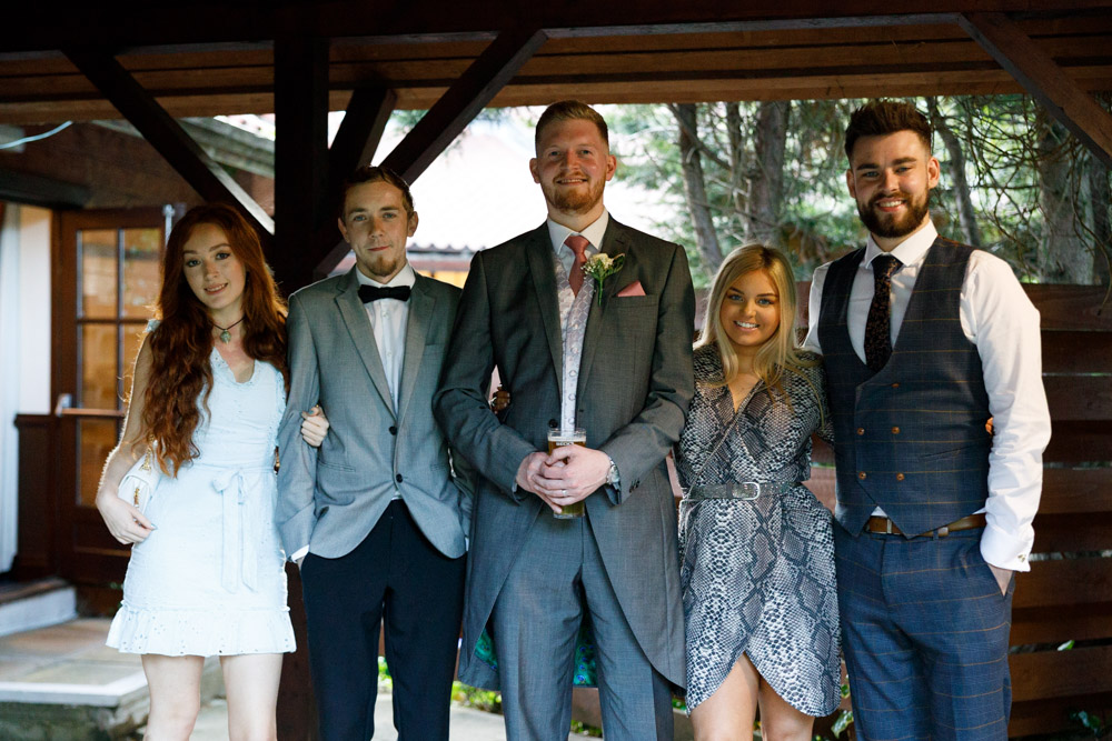 A final casual group photo with friends, taken outdoors as light softens into evening.