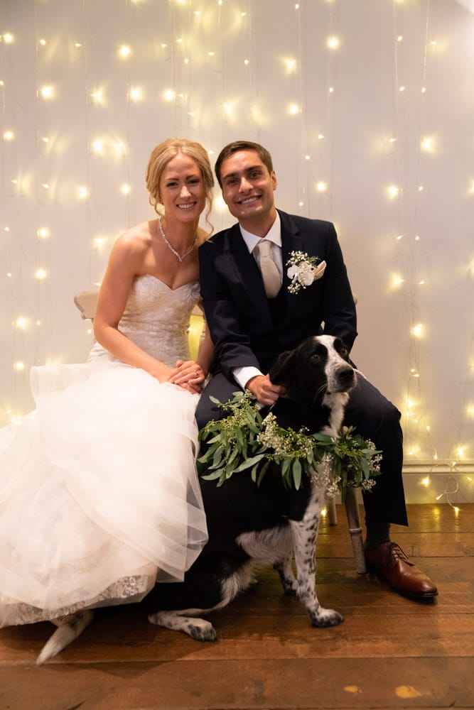 The couple’s dog looks forward to family as guests smile warmly behind.