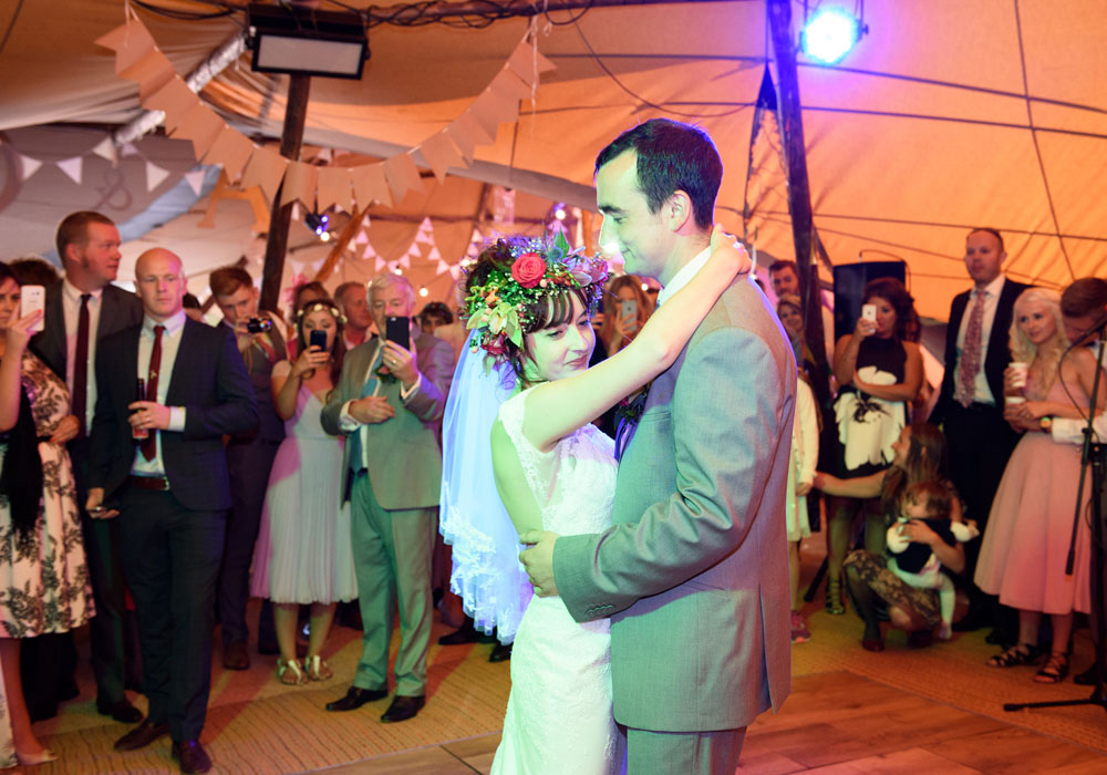 Bride and groom share their first dance surrounded by family and friends.