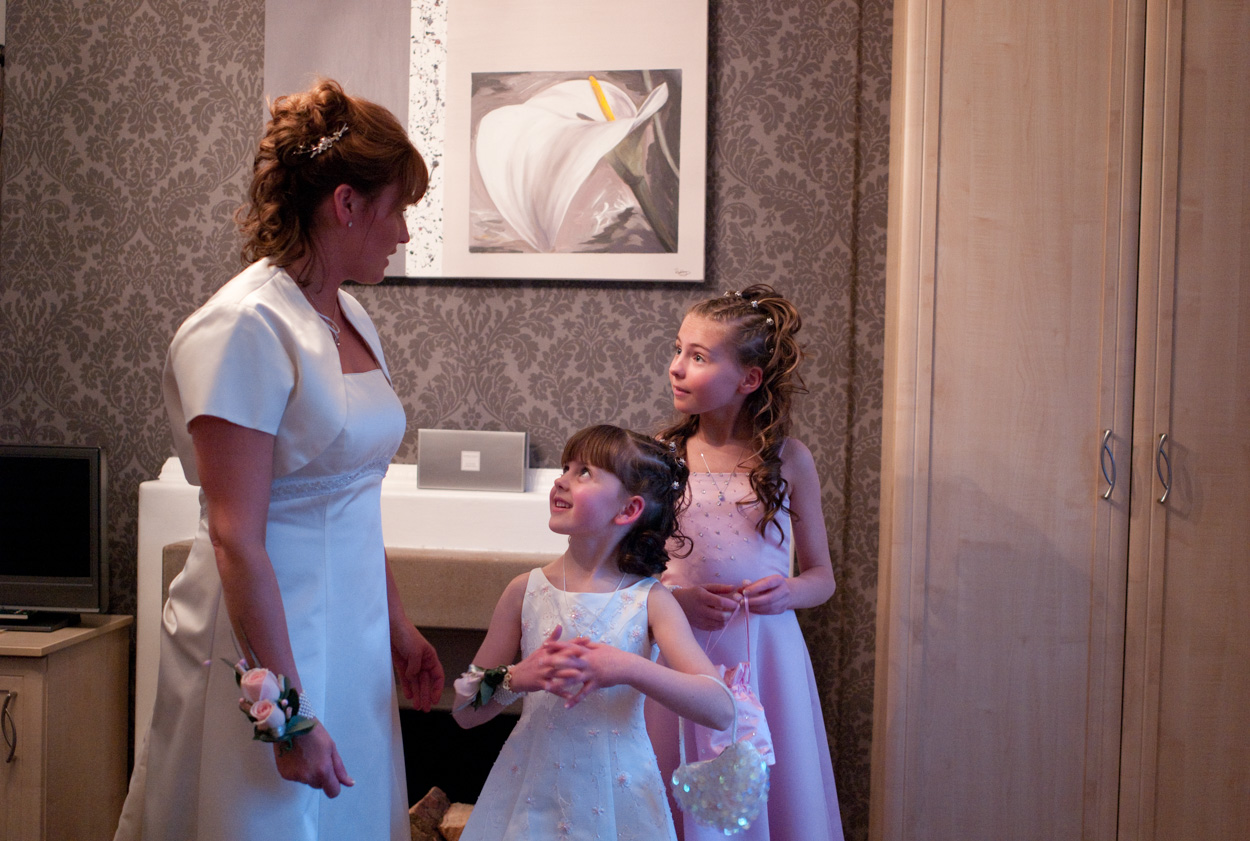 Bride in satin dress talking with her two daughters