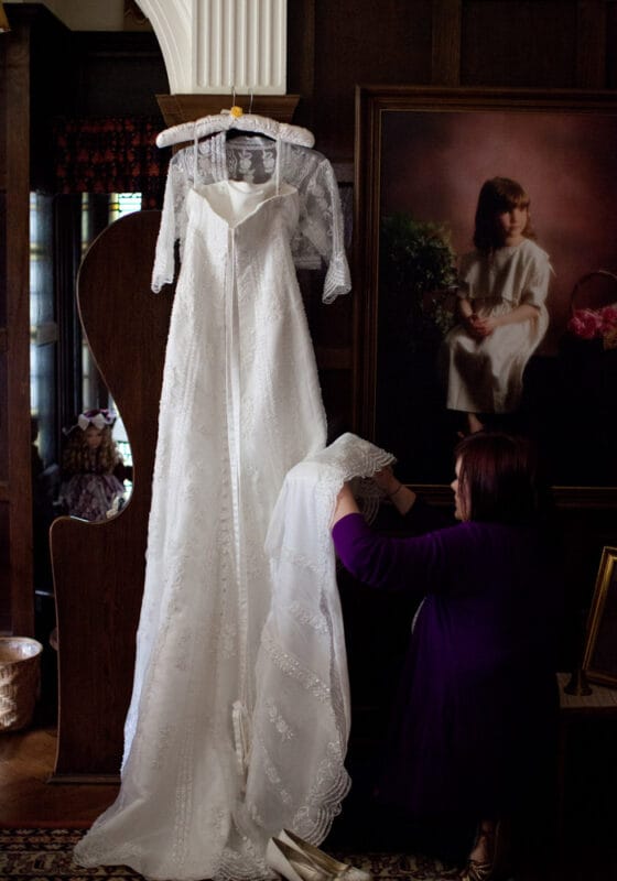 Wedding dress hanging beside a childhood photo of the bride