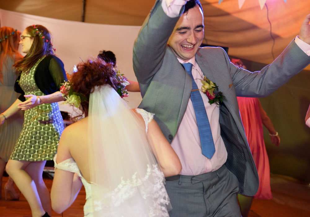 Bride and groom enjoy ceilidh dancing at their West Yorkshire wedding.