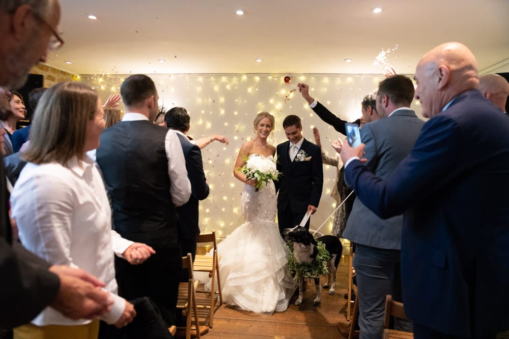 Couple begin walking down the aisle together at the Chilli Barn as confetti is thrown.