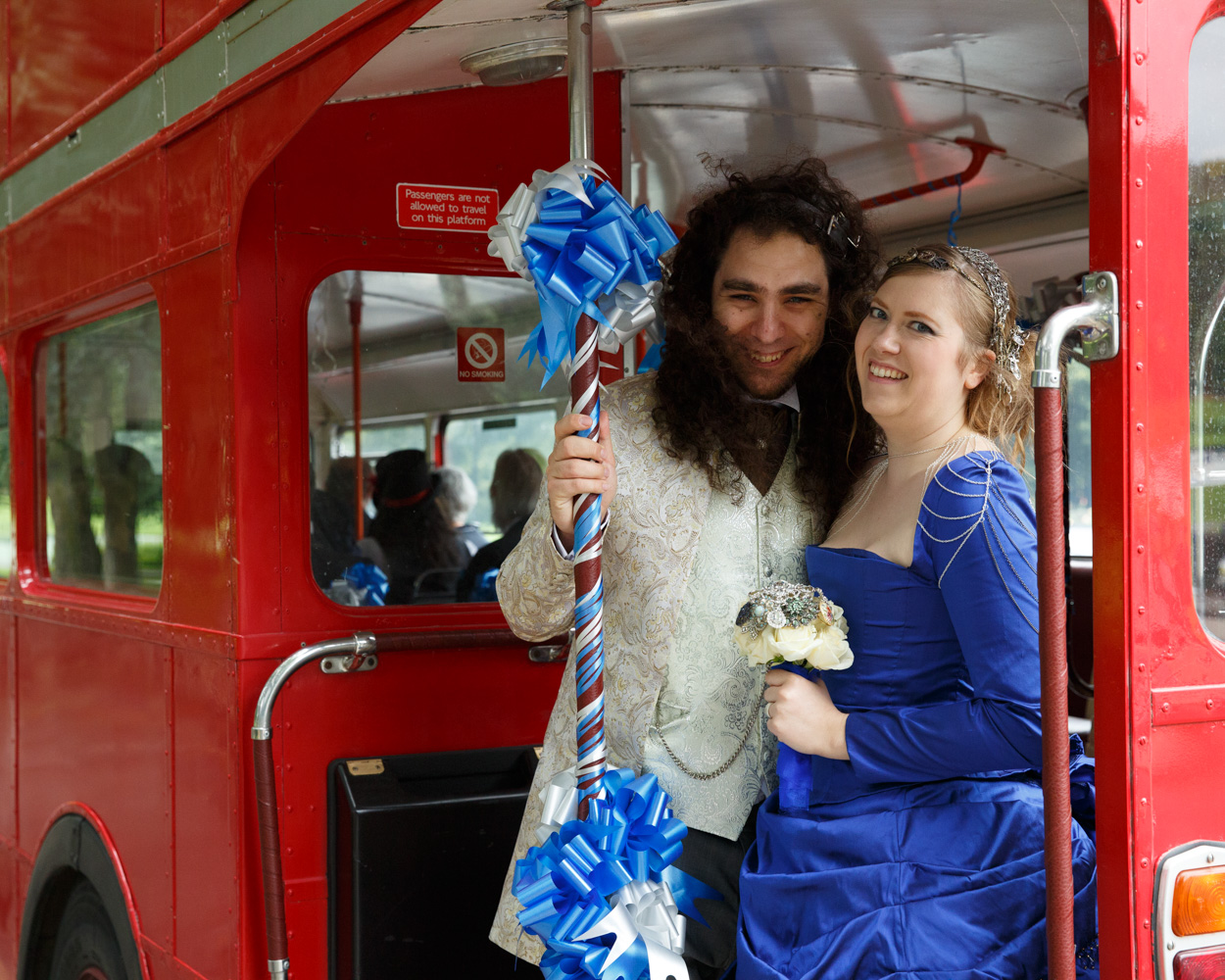 The couple sit together casually on the steps beside their wedding bus