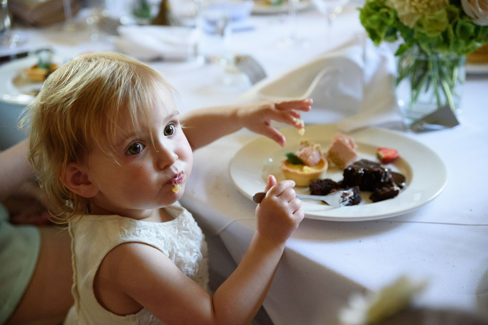 Little toddler eagerly tucks into the tasty wedding food.