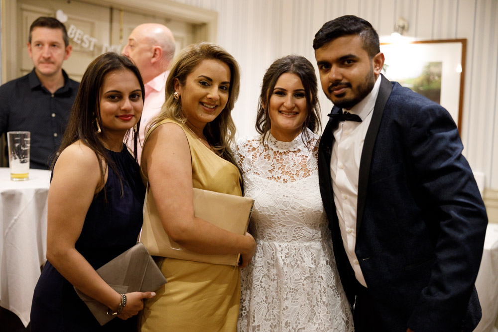 Kyra poses with her family, standing together in the warm reception room light.