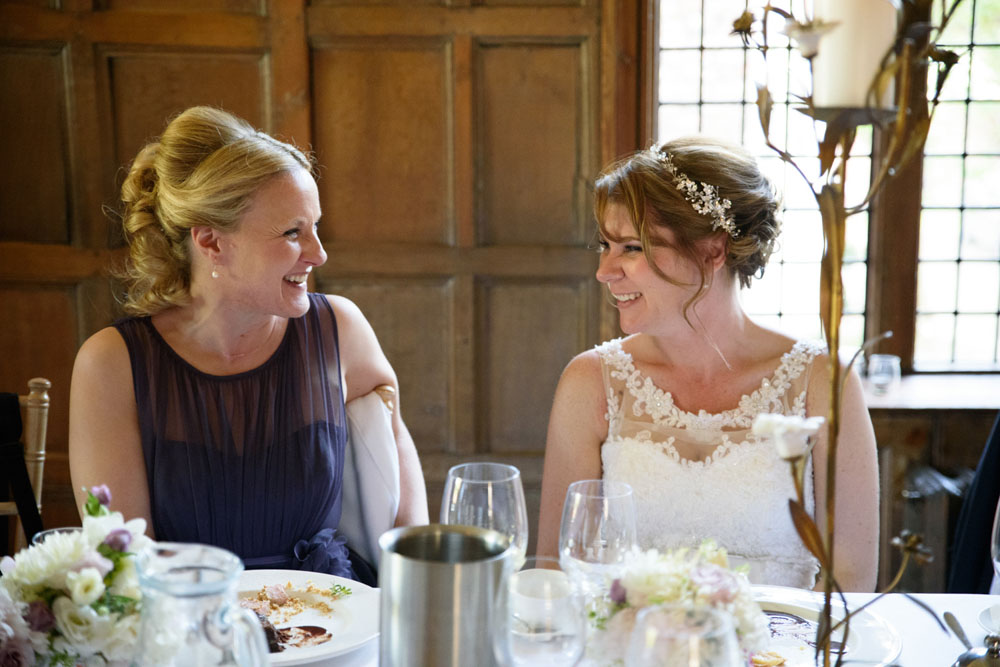 Bride and her sister sit together, smiling warmly.
