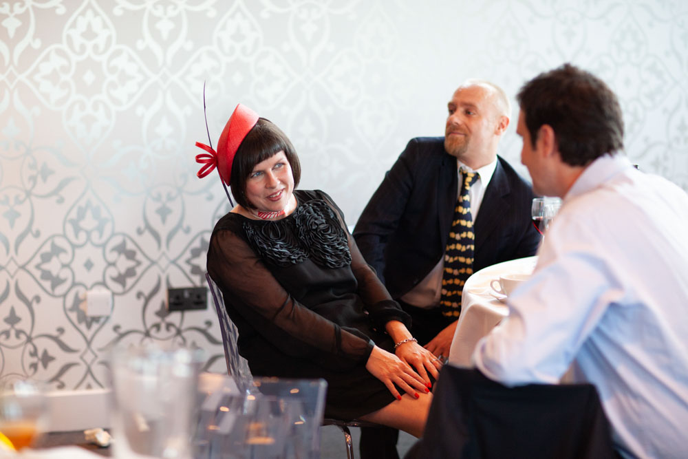 A stylish female guest with a pink hat poses for a candid photo.
