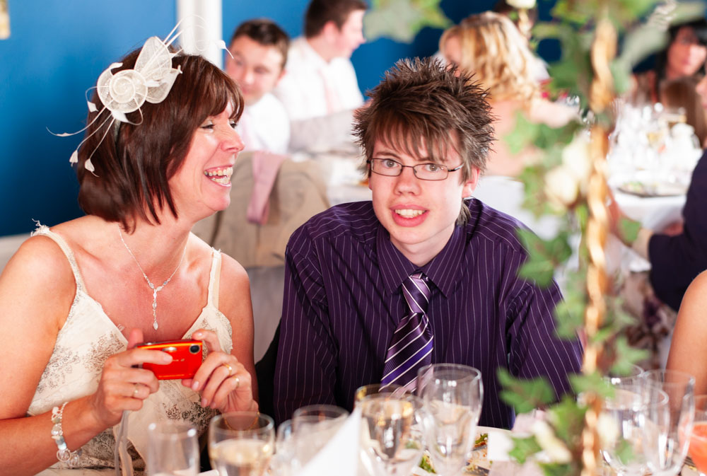 Wedding guests enjoying themselves at the table, one smiling directly at the camera