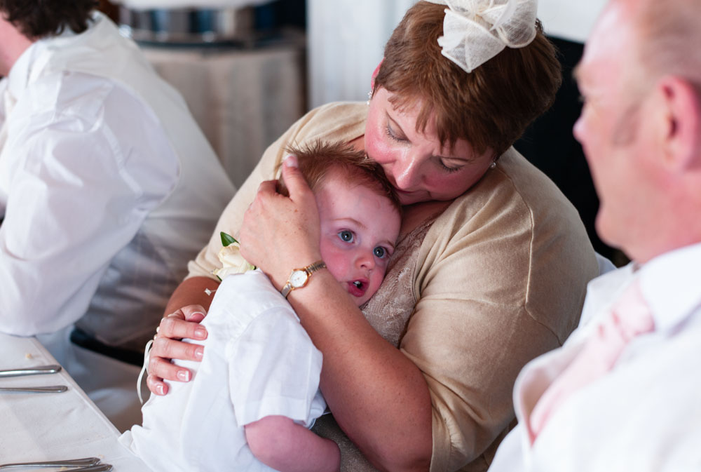 Mother of the bride hugs her grandson during the wedding reception