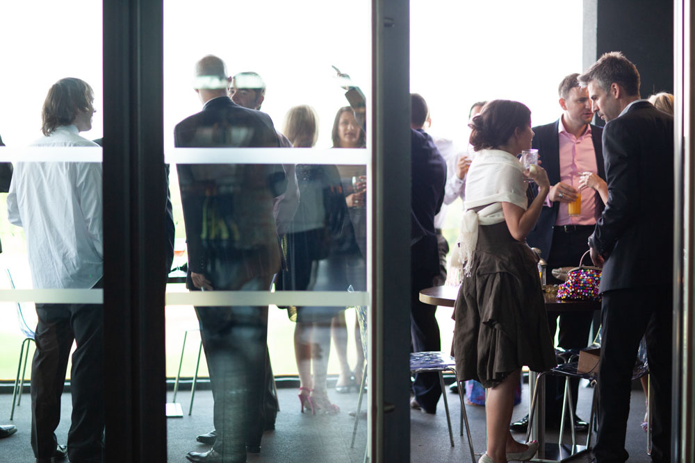 Guests gather on the venue’s balcony area, chatting and enjoying the late sun.
