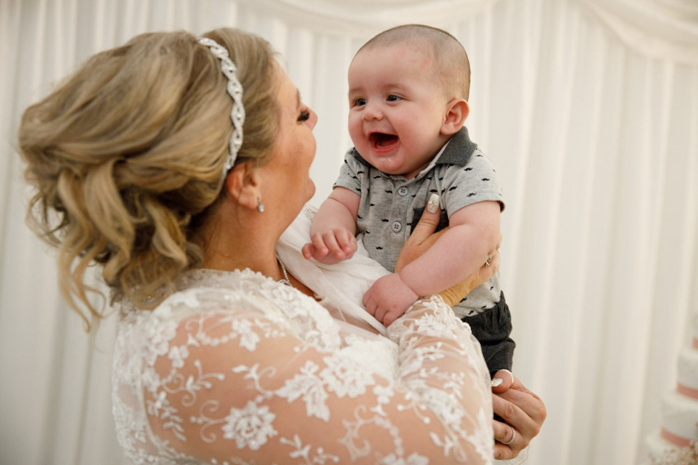 Tracy gestures sweetly to a baby, who smiles back at her.
