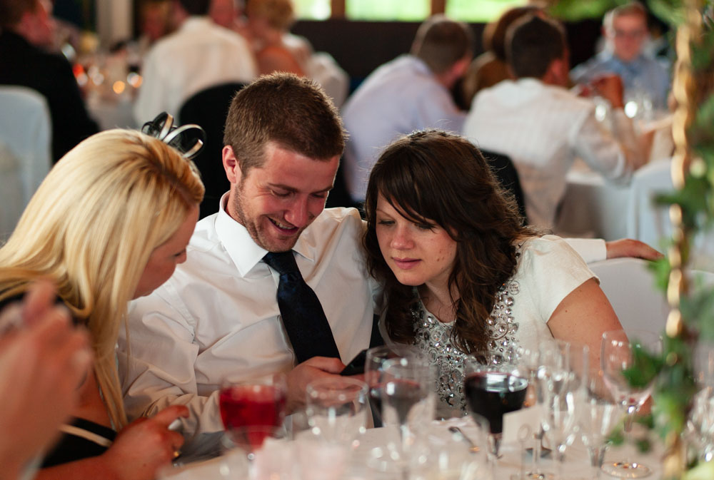 Three guests share a moment, heads together looking at a phone