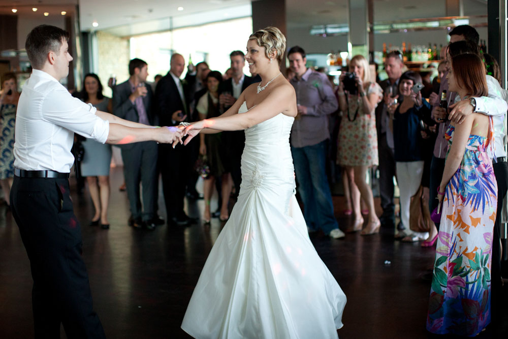 Sam and Tim share their first dance surrounded by supportive guests at the edges.