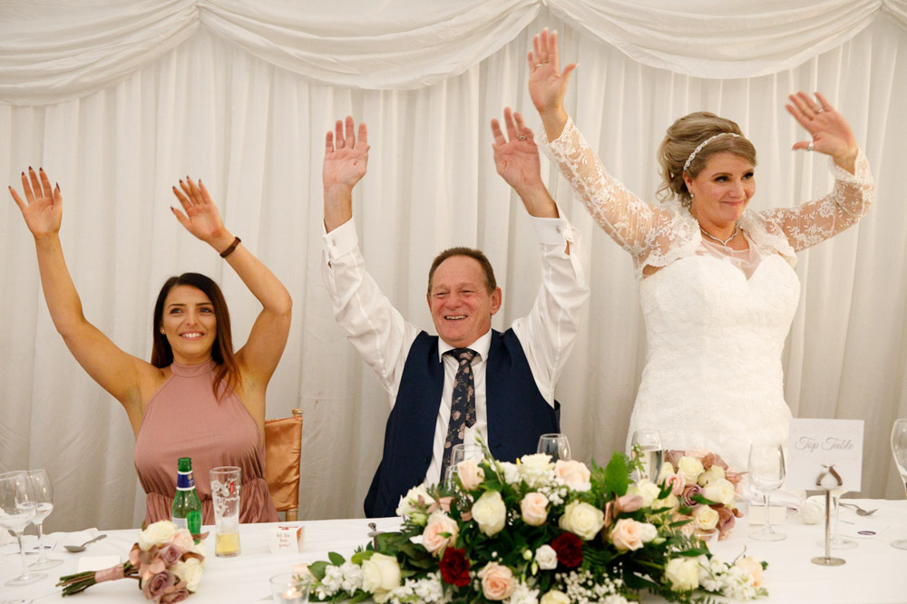 Top table smiling with raised arms, fully joining in the fun.