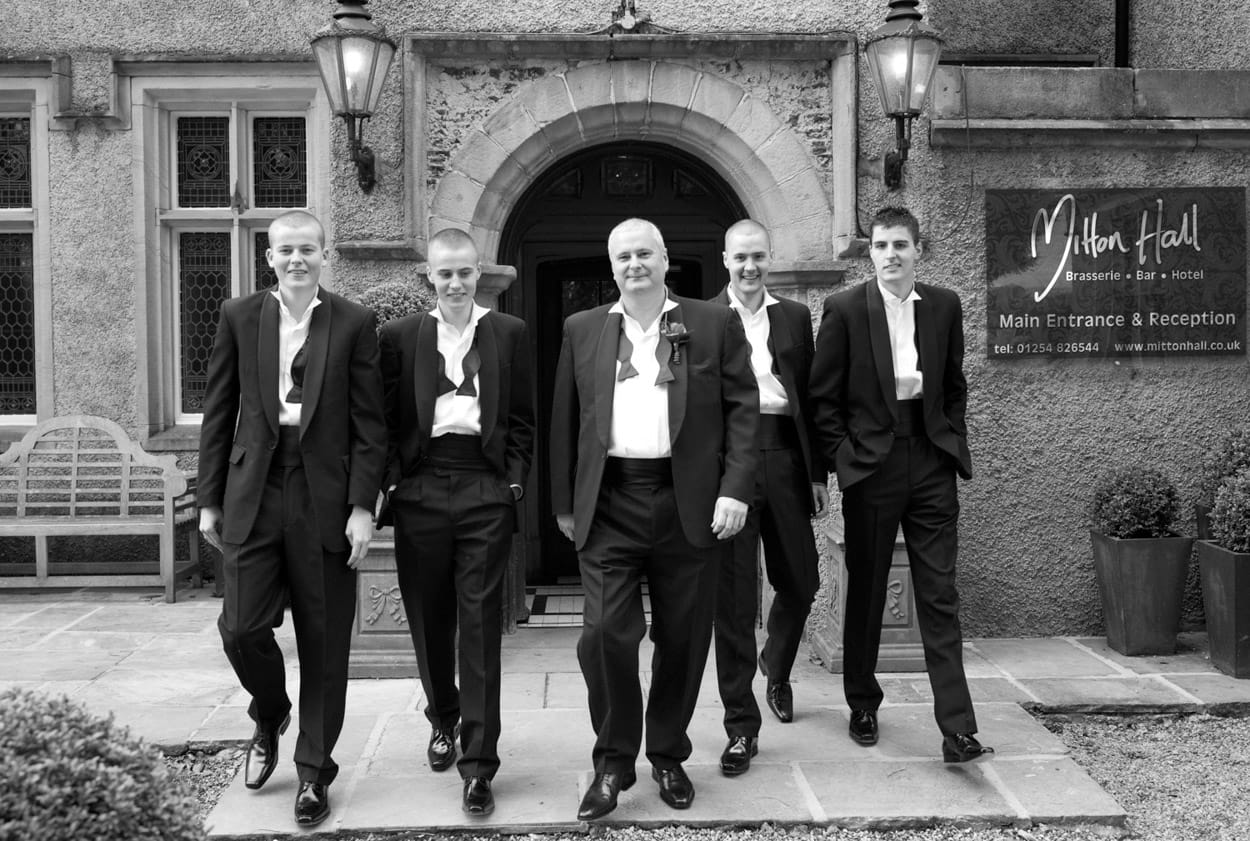Black and white photo of the groom walking toward the camera with his sons in a Reservoir Dogs style.