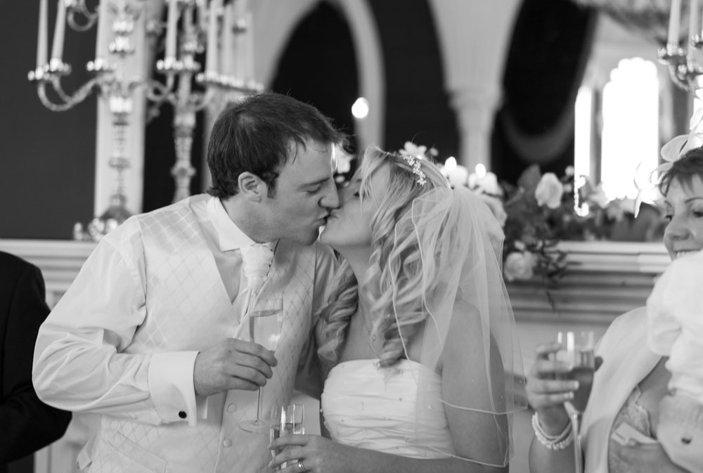 The groom kisses Vicky in black and white before beginning his speech
