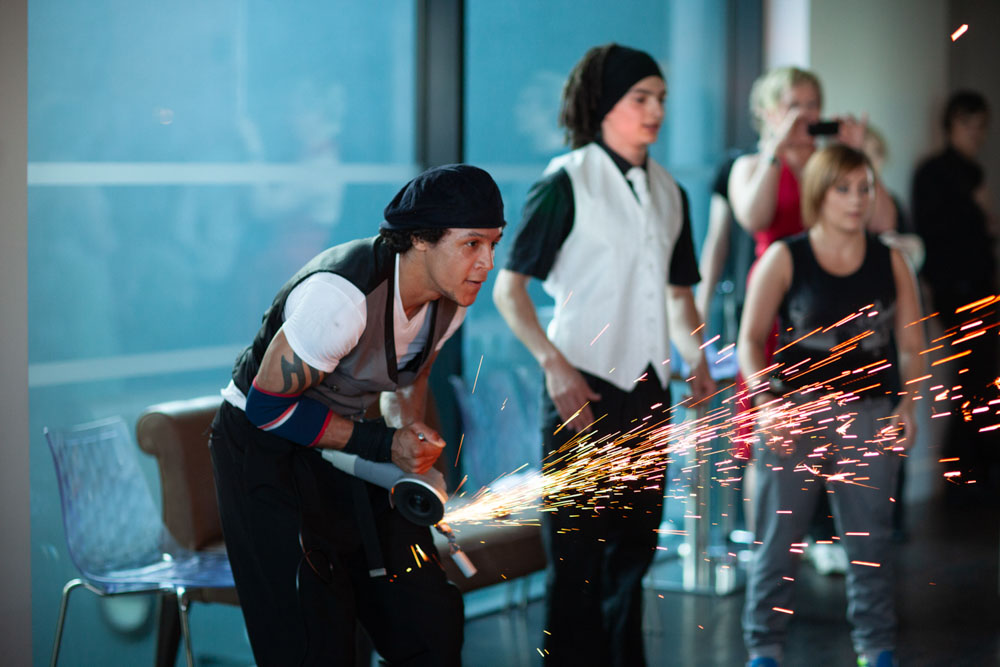 Sparks fly as a metal bar is cut with a grinder during the dance show.