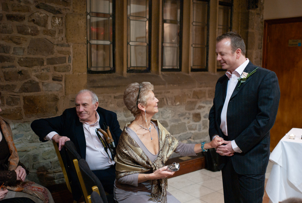 Groom smiling with his mother in the ceremony room