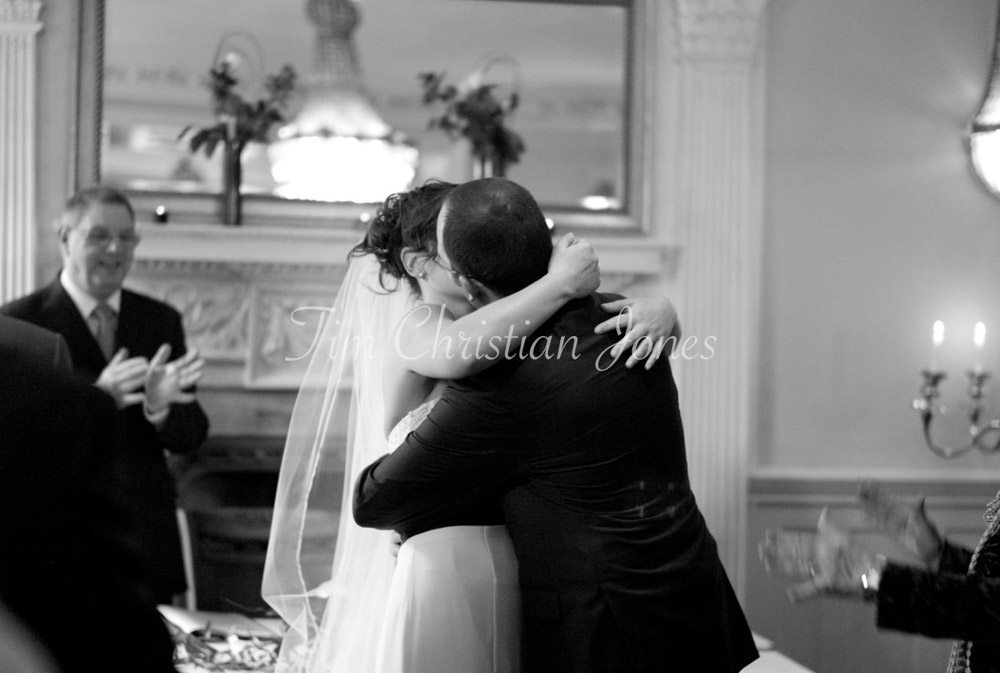 In black and white, the couple embrace tightly, laughter spilling from their kiss.
