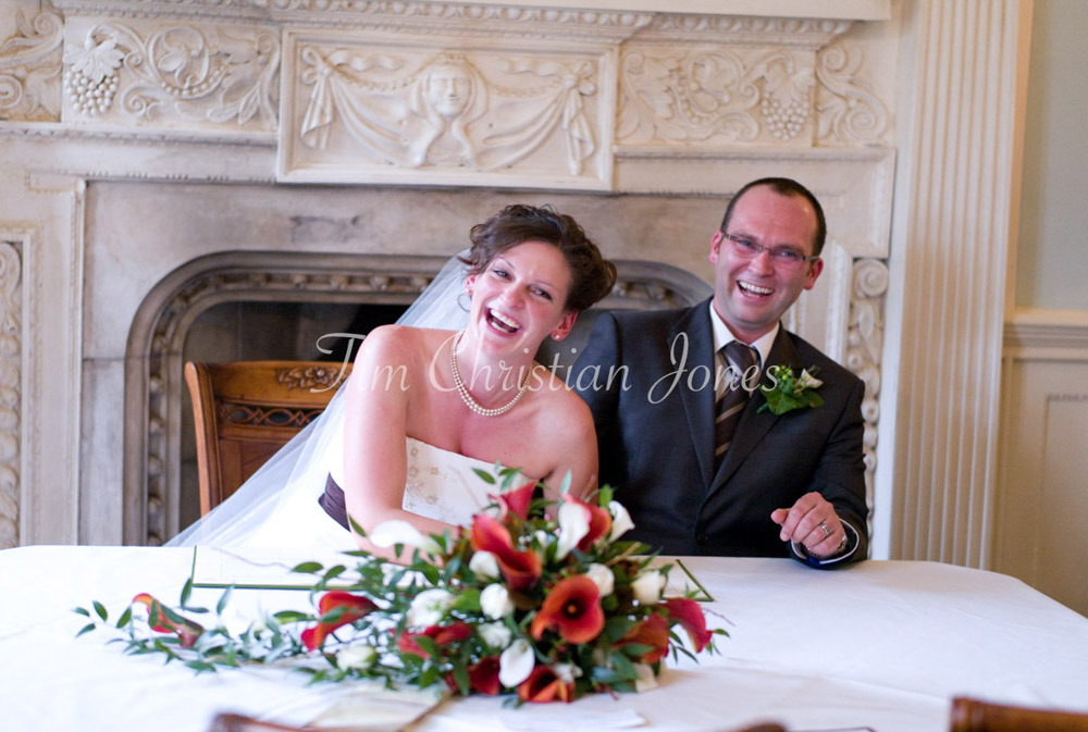 Julie and Pat laugh while pretending to sign the register, joy radiating between them.
