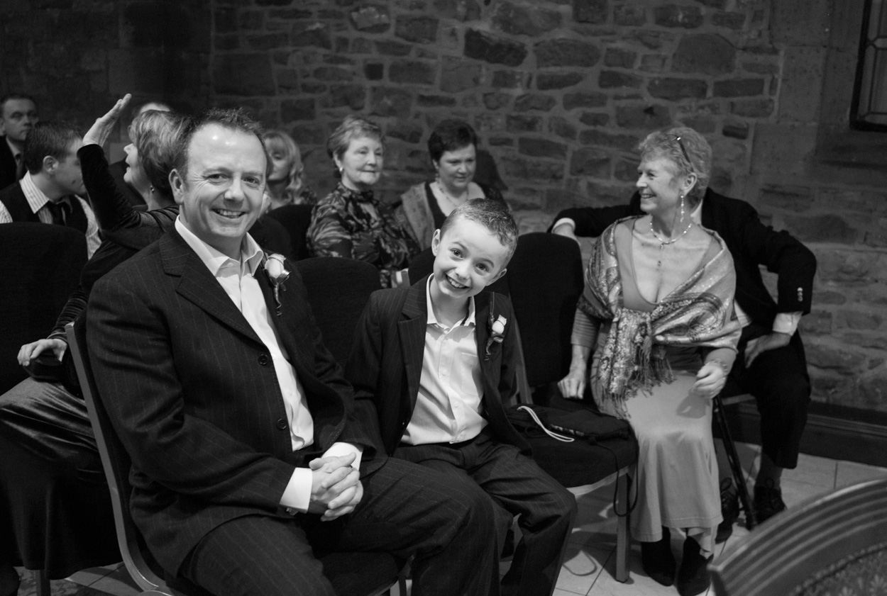 Groom and son seated front row smiling before the ceremony