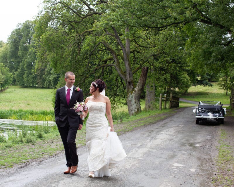 Couple walking side by side down a narrow road on a cloudy wedding day