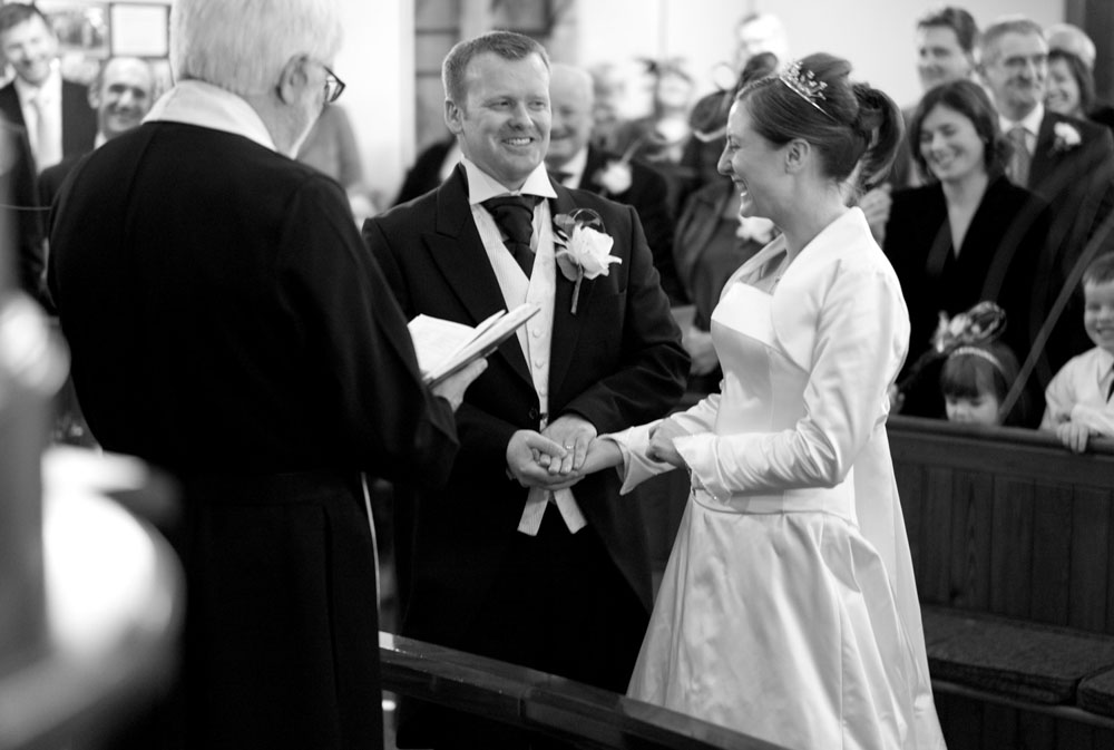 The couple hold hands and smile during their wedding vows.