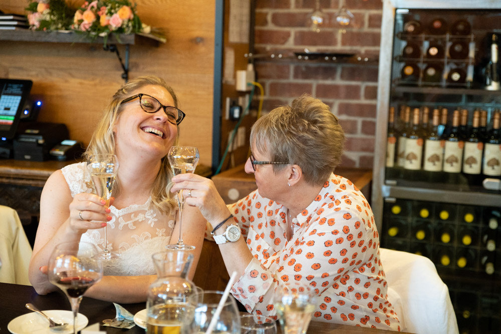 The couple smiling with white wine flutes in hand