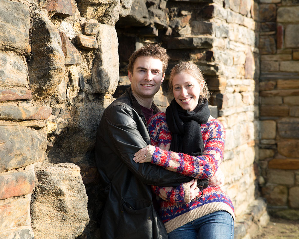 Zoe and Andrew glowing in the evening sun, sitting close against the old rock walls at Kirkstall Abbey.