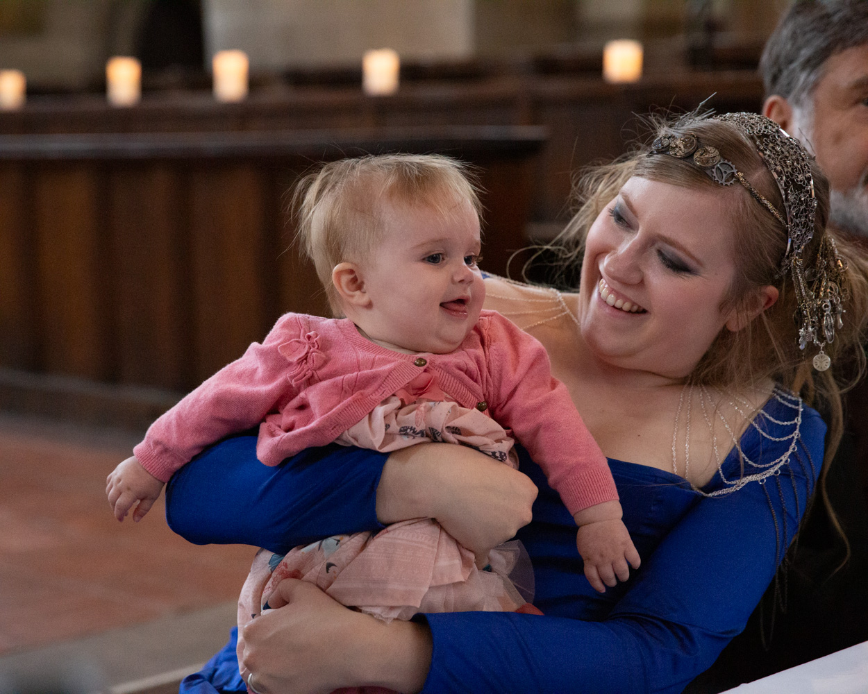 The bride smiles while holding her cousin’s baby
