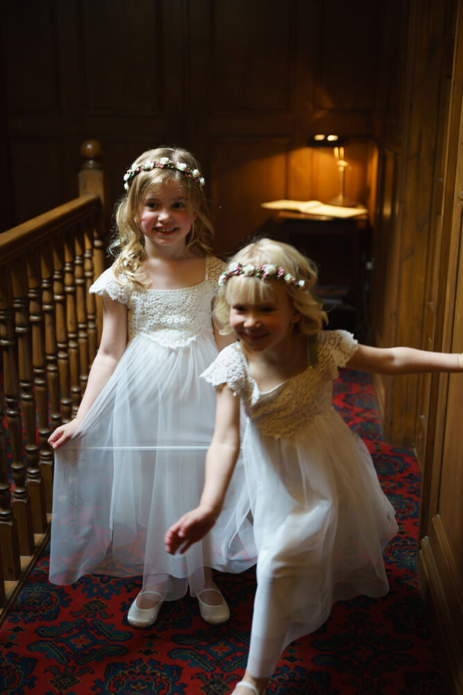 Little bridesmaids all ready in their dressed - posed for a photo - one tired to escape making a lovely candid moment captured by a Leeds, West Yorkshire wedding photographer
