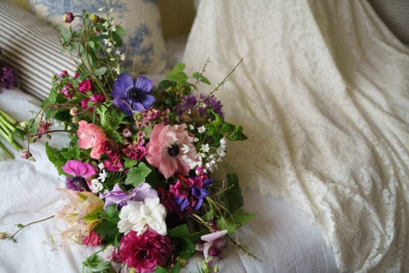 Bride’s summer bouquet placed beside her wedding dress
