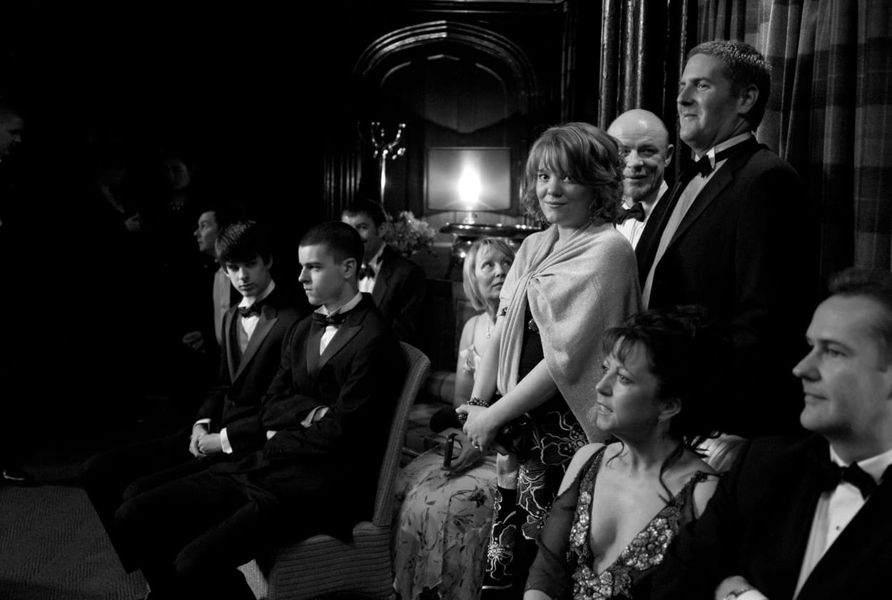 Black and white photo of guests waiting on sofas before the ceremony.