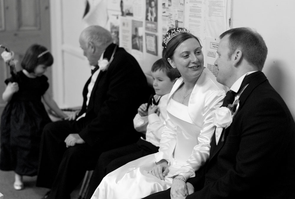 The bride and groom smile at one another as they sit at the register table.