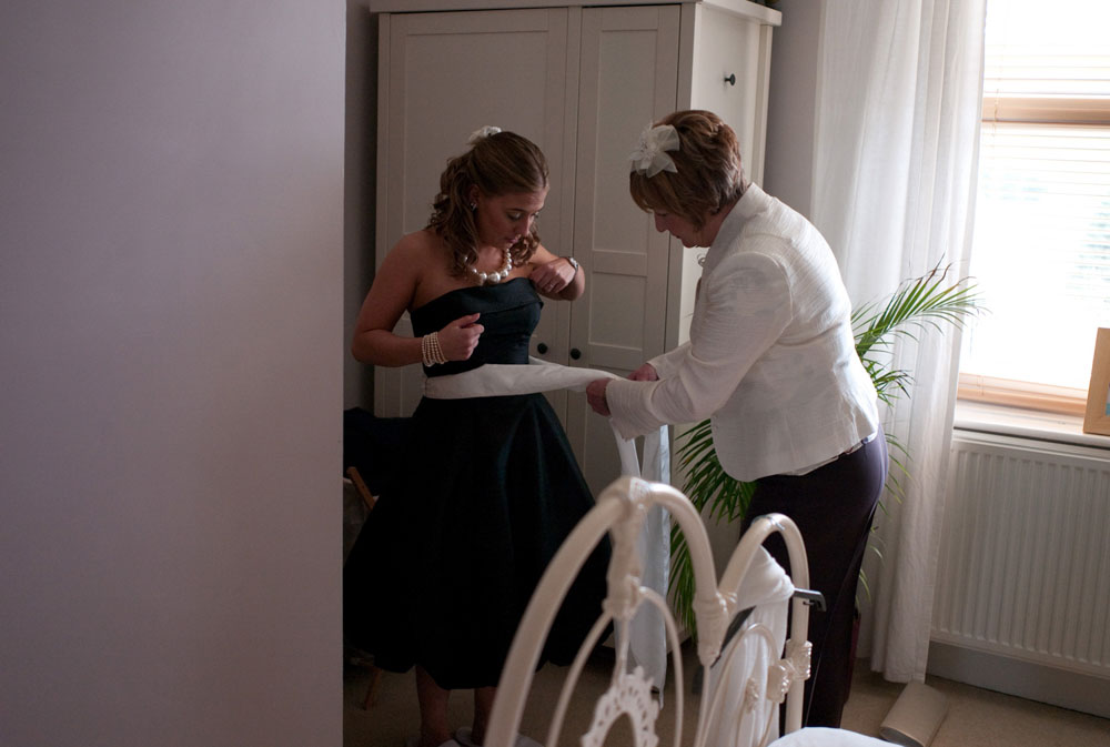 The bride's mom helps a bridesmaid tie her dress - Hoyle Court wedding photography