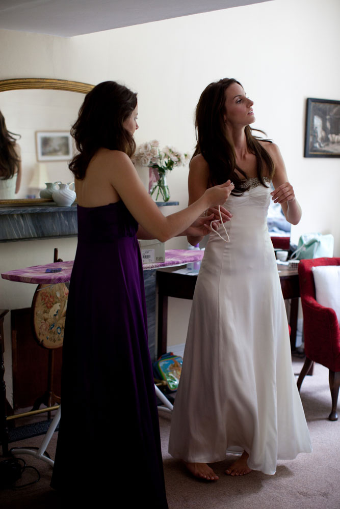 The bridesmaid, the bride's sister helping with jewellery by Wedding photographer Yorkshire