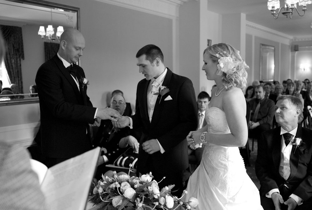 Best man passes the groom the bride's wedding ring