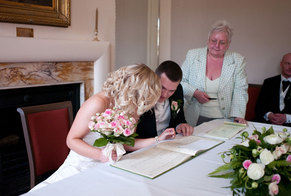 The couple check the register before signing - Hoyle Court wedding photography