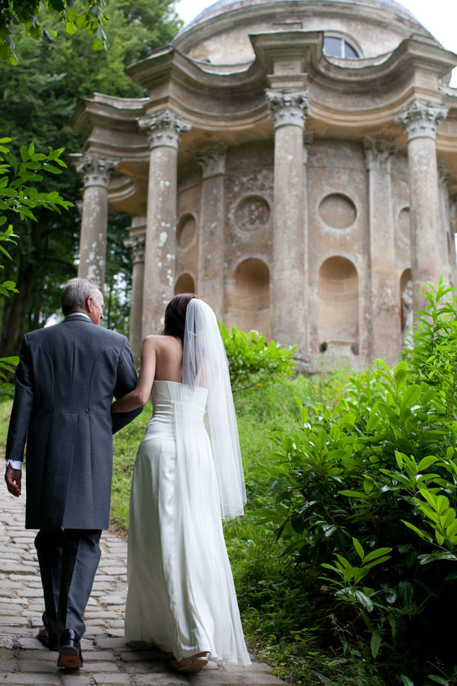 From behind, the bride with her father and the Temple of Apollo in the background