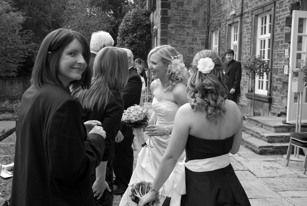 Guest looks at me taking a photo of the bride chatting - Hoyle Court wedding photography