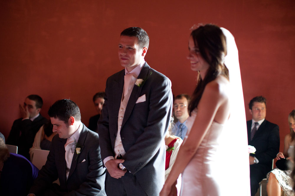 The bride and groom smile at the registrar