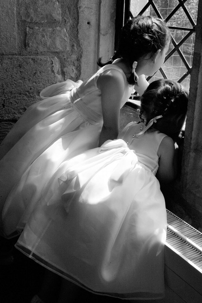 Bridesmaids in black and white looking through the venue window - by Leeds, West Yorkshire wedding photographer