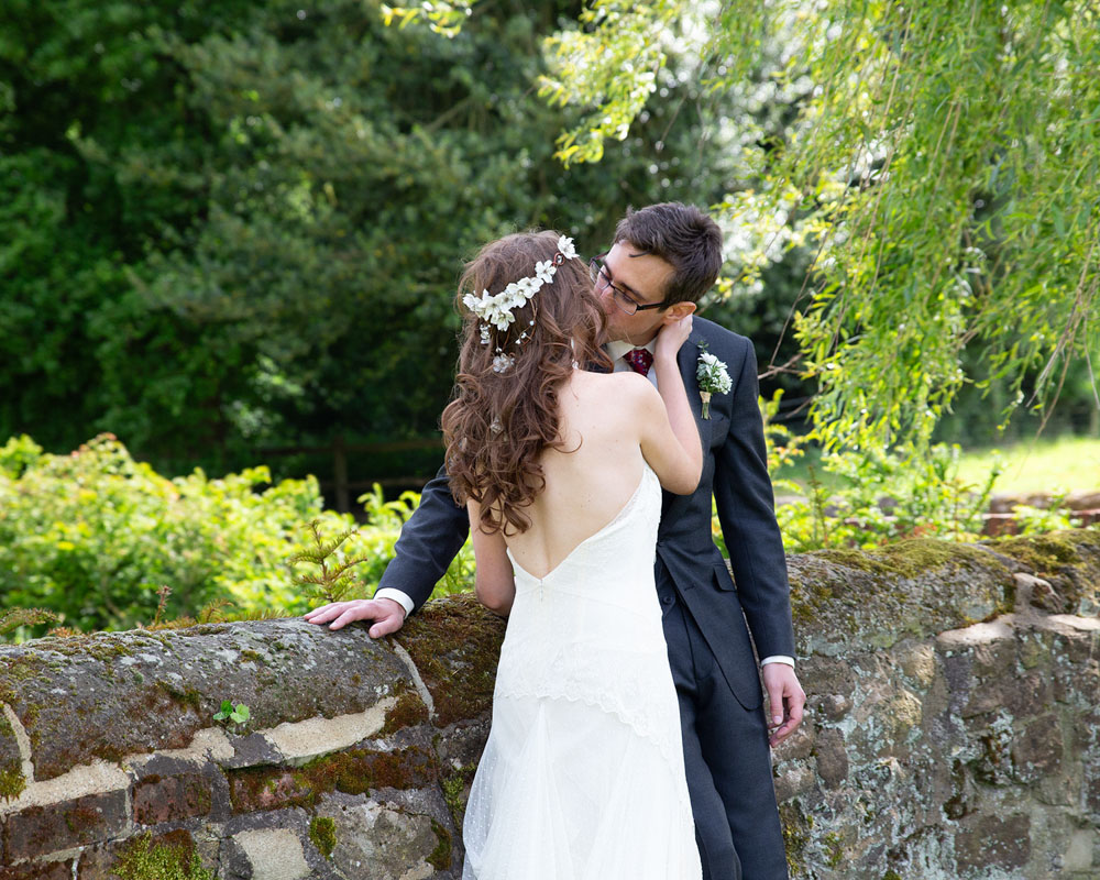 posed by the wall and a kiss of the bride and groom - Natural Yorkshire wedding photographer