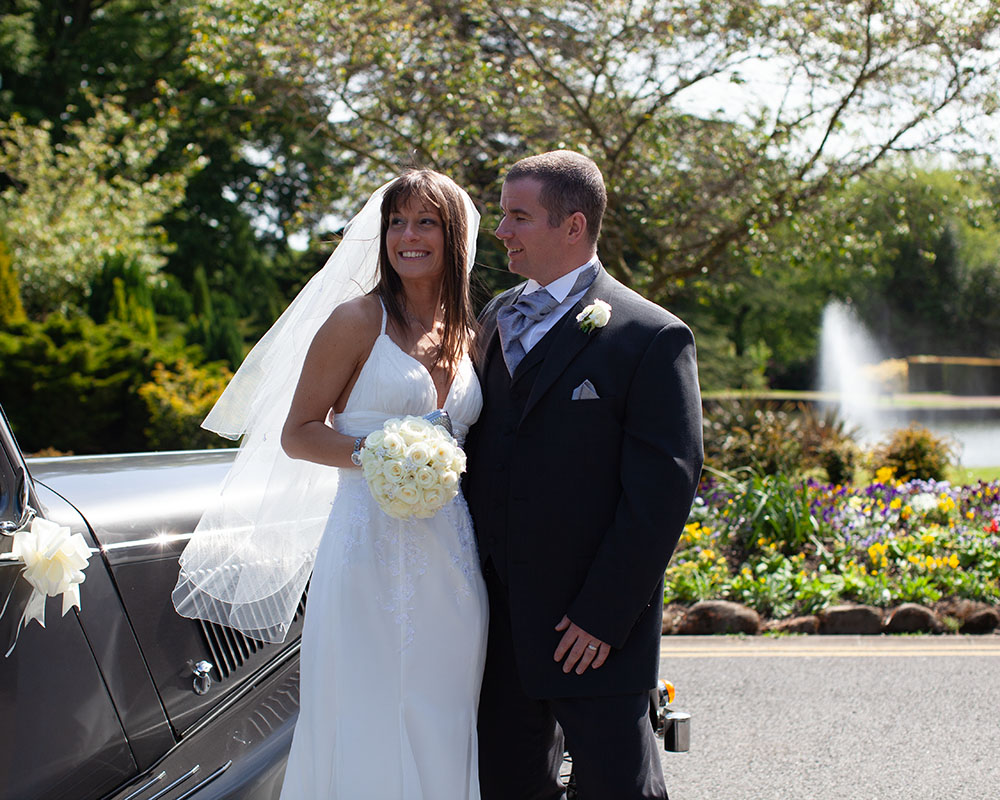 The couple in sunshine by the car and water - wedding photography Leeds