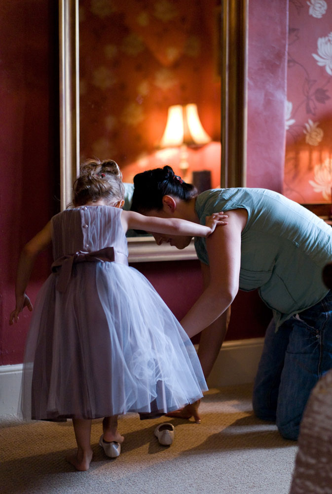 Bridesmaid putting on her shoes with help from mom