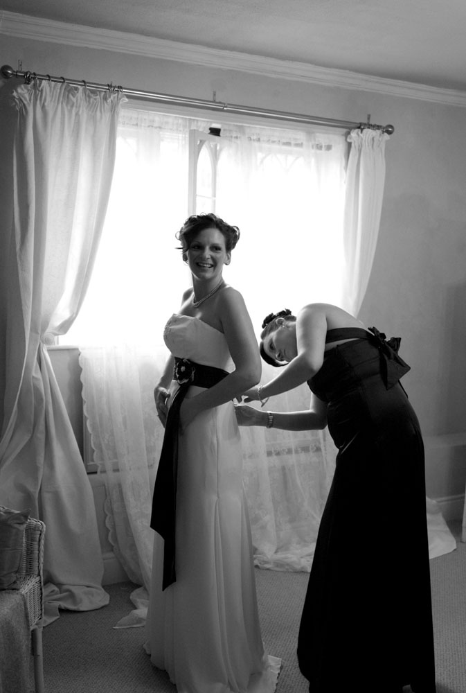 The bride's sister helping tie the wedding dress ribbon